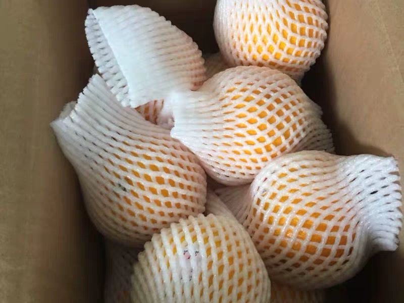 一张木质桌面上摆放着打开的金堂脐橙精品礼盒,内有六颗光泽诱人的脐橙,旁边有一颗切开的橙子,露出饱满多汁的果肉,几滴果汁正缓缓滑落,背景虚化的果园暗示其产地来源 金堂脐橙礼盒与新鲜果实特写