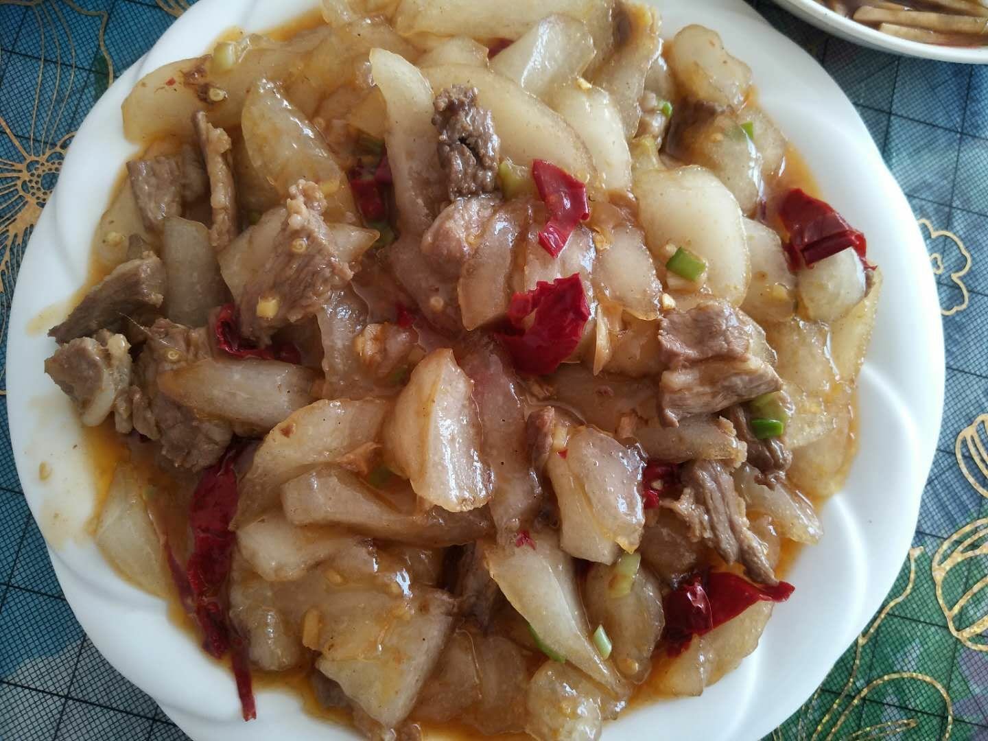 一盘精致的凉拌蒿子杆,菜肴呈翠绿色,整齐码放在白色瓷盘中,表面淋有透明油光酱汁,点缀着蒜末、红辣椒圈和白芝麻,旁边配有柠檬片装饰,整体清新诱人 凉拌蒿子杆成品图