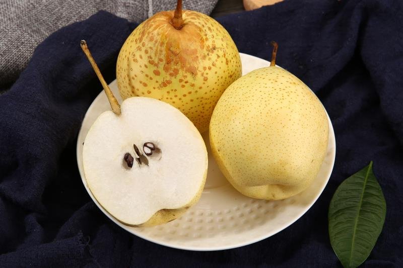 切好的鸭梨果盘特写,展示果肉洁白、质地细腻、汁水丰富 一盘切好的鸭梨果片摆放在白色瓷盘中,旁边搭配薄荷叶和柠檬片,背景为明亮厨房台面,整体呈现清新健康的饮食风格