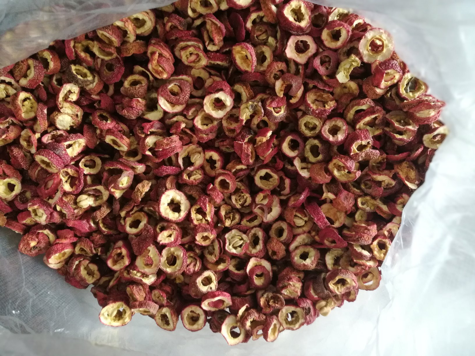 左侧为干燥的红色山楂切片,表面皱缩,有灰白色小斑点;右侧为黄色或黄绿色的鸡内金,呈不规则卷曲片状,质地脆,有光泽,边缘薄而透明,带有轻微腥味 山楂与鸡内金药材对照图