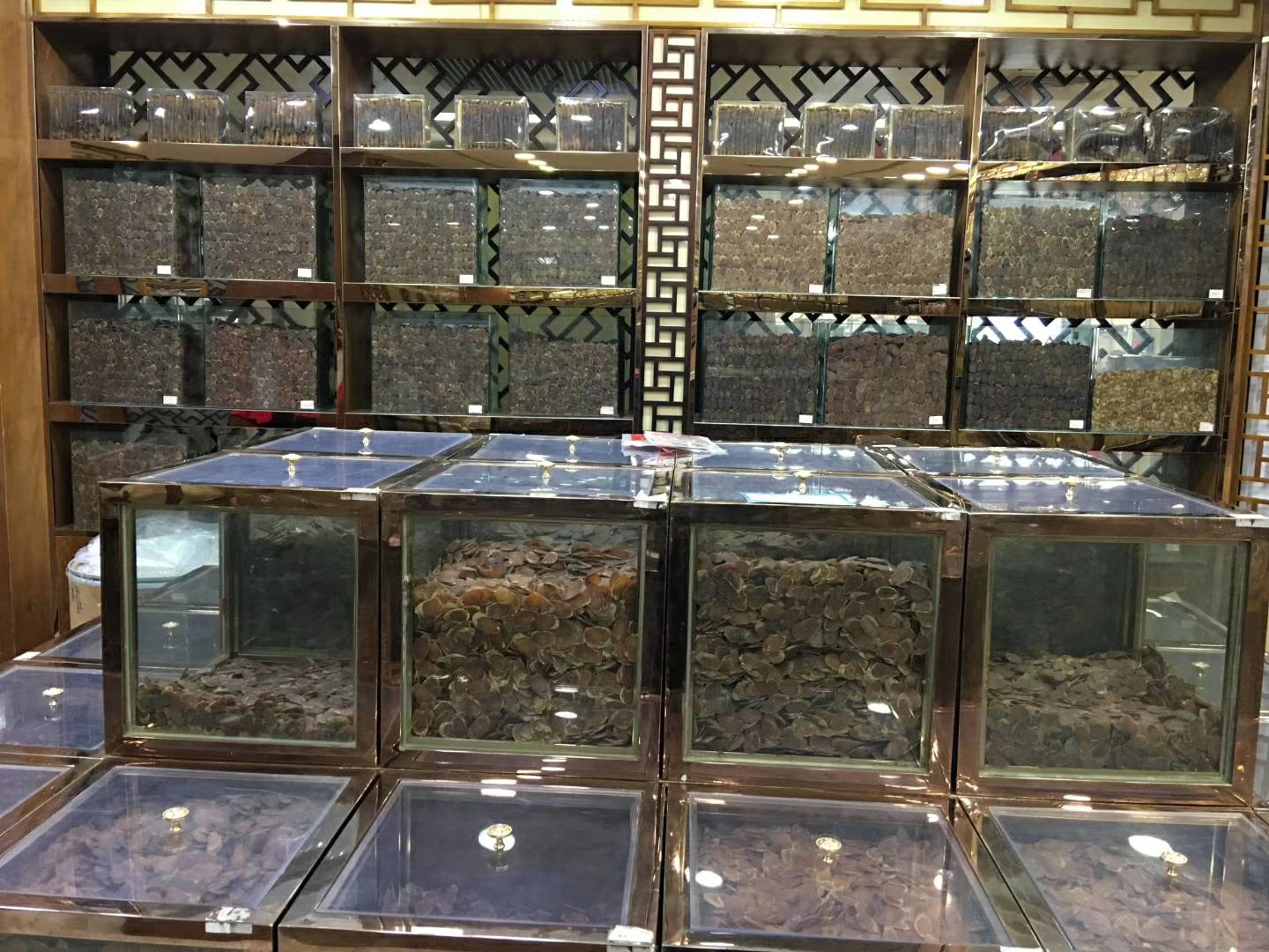 一个古色古香的中药铺场景,木质药柜上整齐排列着多个抽屉,其中一个标有‘红参’的抽屉拉开,露出切片红参,呈深红褐色、半透明状;旁边另一个抽屉标有‘人参’,内为人参切片,颜色较浅呈米白至淡黄色;桌上还摆放着戥子秤、研钵和中医典籍,整体氛围体现传统中医药文化 传统中药房中的红参与人参对比陈列