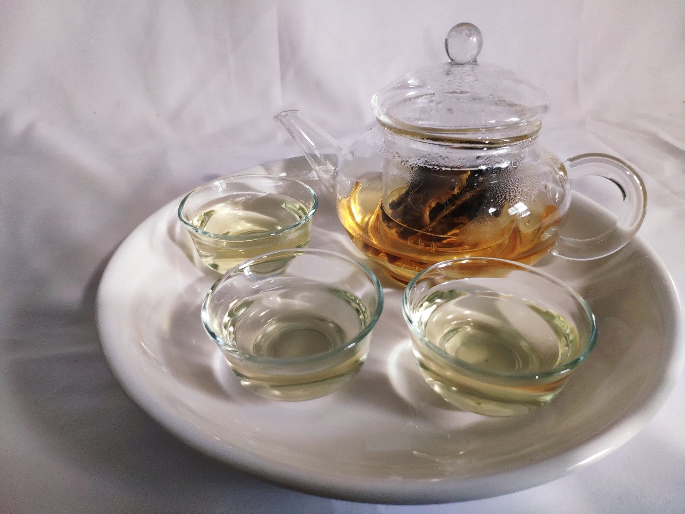 一位传统匠人正在陶罐中熬煮姜母茶,锅中翻滚着切片的老姜与黑糖,蒸汽升腾,桌上摆放着干燥姜片和成品瓶装姜茶,背景为古朴厨房环境 传统姜母茶熬制过程场景