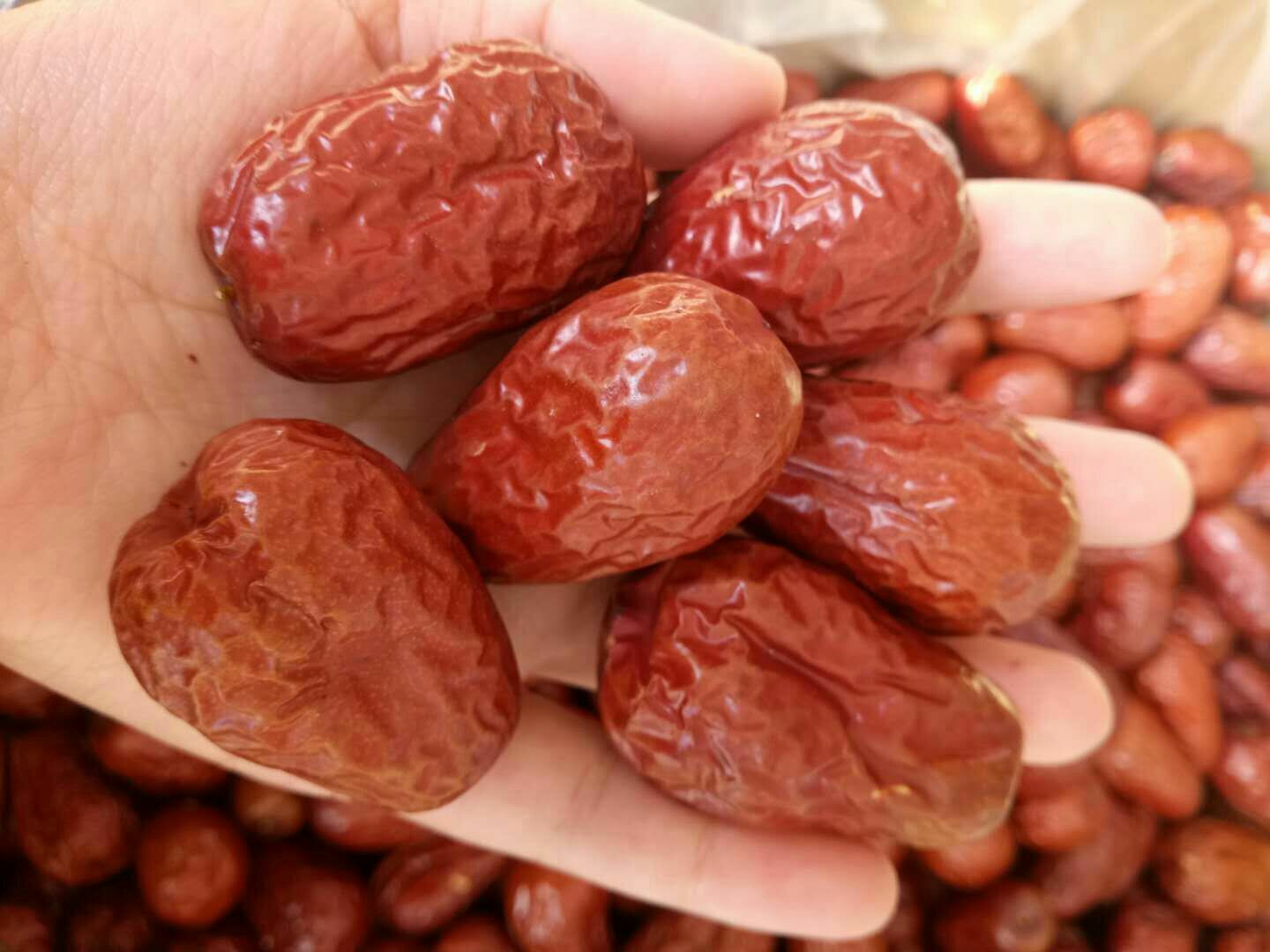 新鲜采摘的皮皮枣整齐摆放在竹篮中,旁边有一碗淡盐水,一只手正在用小刀对皮皮枣进行纵向切割去核,背景为厨房操作台,光线自然明亮 皮皮枣清洗与去核过程