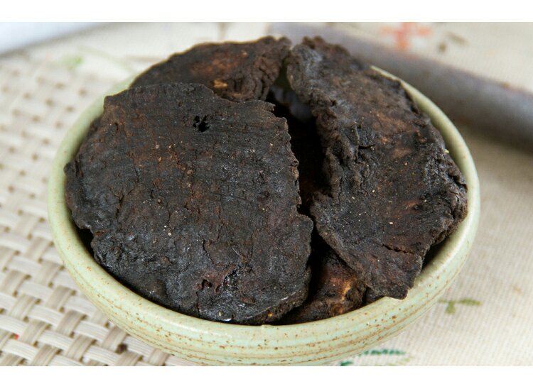 熟地黄饮片特写：棕黑色、油润光泽、断面角质样、可见明显环纹