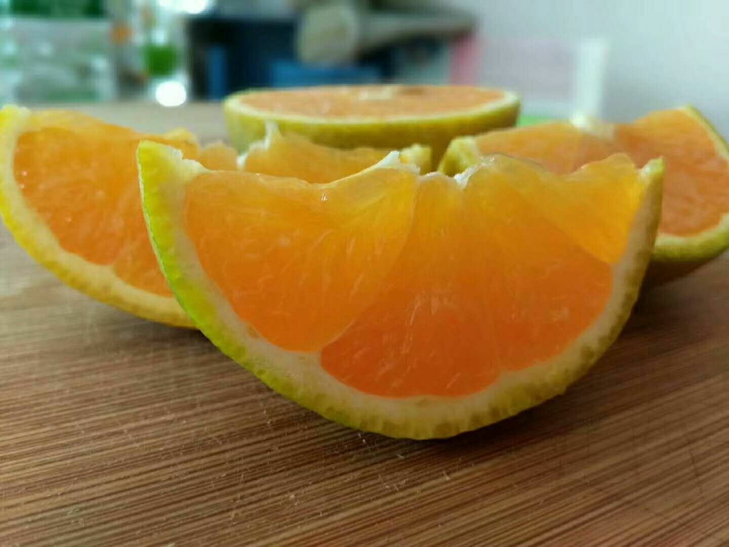 一个新鲜切开的夏橙,露出饱满多汁的果瓣,晶莹的果汁微微渗出,果肉呈明亮的橙红色,纹理清晰,背景为木质砧板,突出食材的新鲜质感 切开的夏橙特写