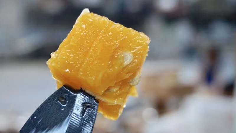 一把锋利的厨刀正在将一个夏橙横向切成均匀的圆形薄片,案板上已摆放数片切好的橙片,光线明亮,突出果肉饱满多汁的状态 夏橙横切过程
