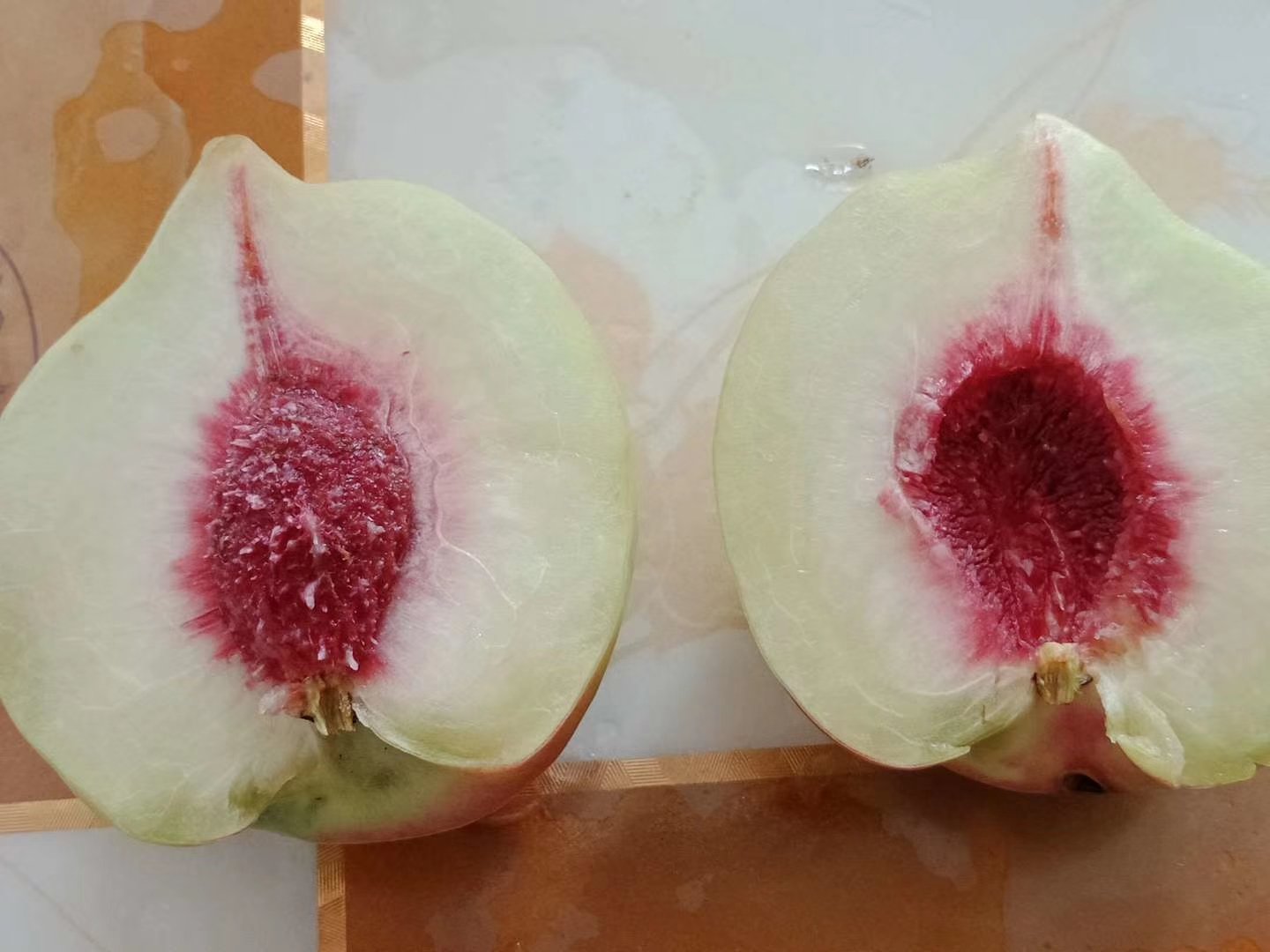 一颗被横向切开的中华寿桃,露出乳白色至淡粉色的果肉,中心核小而清晰,果肉纹理细腻,汁水欲滴,旁边配有尺子显示果实直径约9厘米,背景为白色陶瓷盘,突出果品新鲜与高端质感 切开的中华寿桃特写