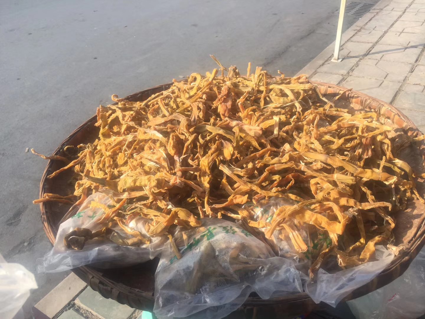 一个乡村集市的摊位上,整齐摆放着数十根带壳的新鲜金竹笋,笋体粗壮,外皮呈现金黄色,部分剥开露出洁白脆嫩的笋肉,旁边配有剪刀和湿布,展示售卖场景 市场摊位上摆放的新鲜金竹笋特写