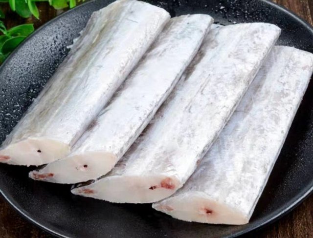 一条新鲜带鱼被从腹部剖开,露出完整的腹腔结构,可见脊柱沿线分布着大片乌黑色薄膜,紧贴腹壁,质地光滑,未见腐败迹象,周围组织呈淡粉色,内脏已清除 带鱼剖开后腹腔内部特写