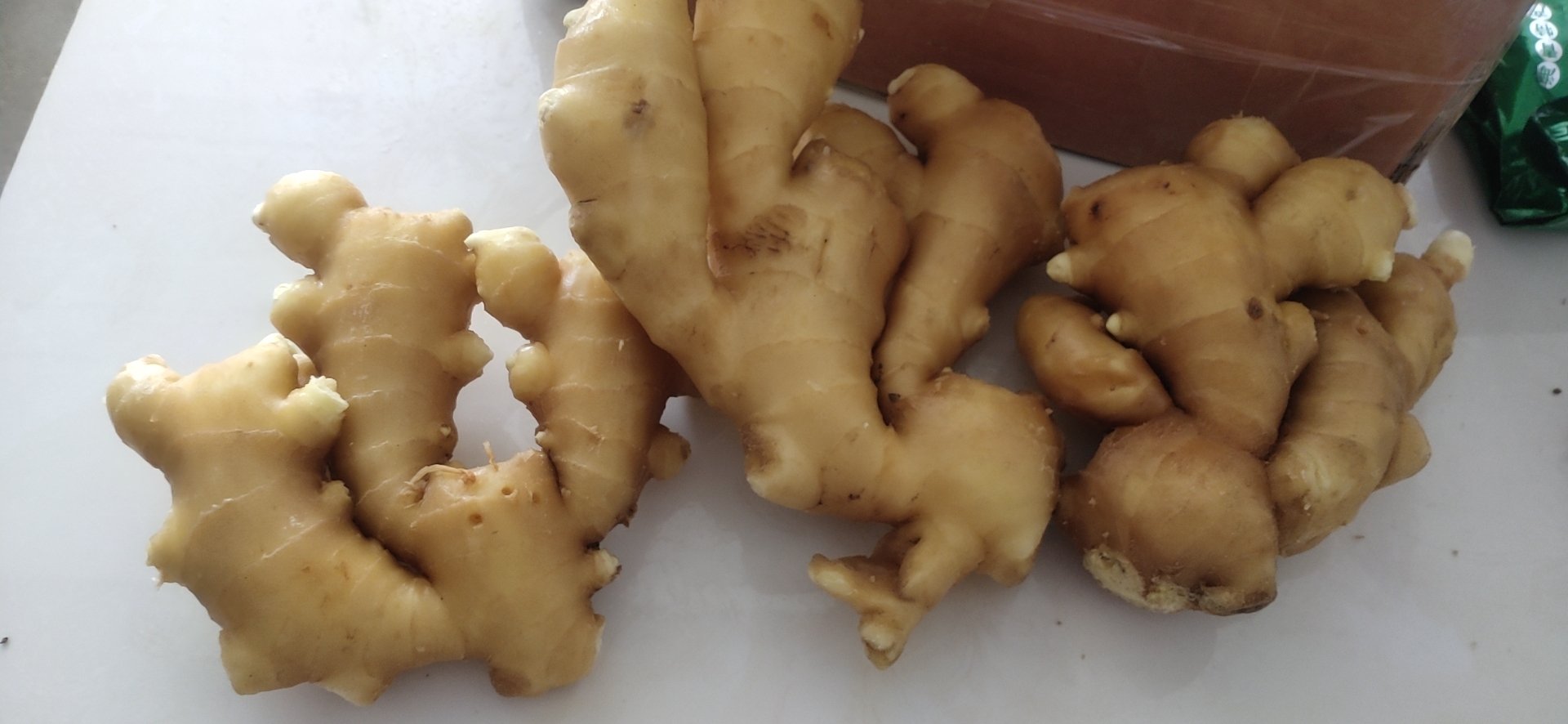 并列摆放三种姜:左侧为小黄姜(个头小、皮色淡黄)、中间为红爪姜(略大、带红色芽尖)、右侧为老黄姜(块大、表皮粗糙深黄),下方标注名称,背景为木质餐桌,突出不同姜种的形态差异 小黄姜与其他姜类对比图