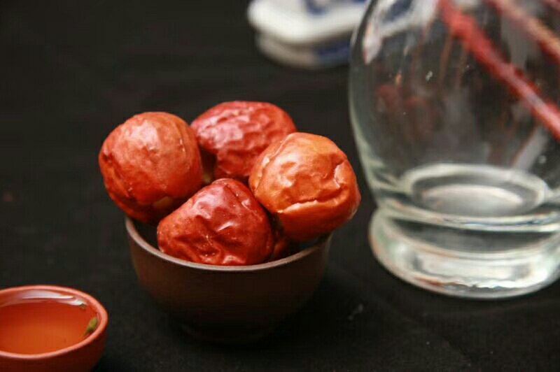 一名身穿白色实验服的技术人员正在使用高效液相色谱仪(HPLC)检测试管中的红枣提取液,屏幕上显示成分分析曲线图,旁边摆放着标有‘脆枣样品’的玻璃瓶 实验室检测人员操作仪器分析红枣成分