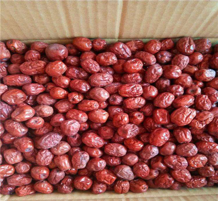 现代化食品车间内,一条全自动夹心枣生产设备正在运行,机械臂精准地将金丝小枣去核并注入白色膏状馅料,传送带两侧有质检人员监控,背景可见包装区域 自动化夹心枣生产线