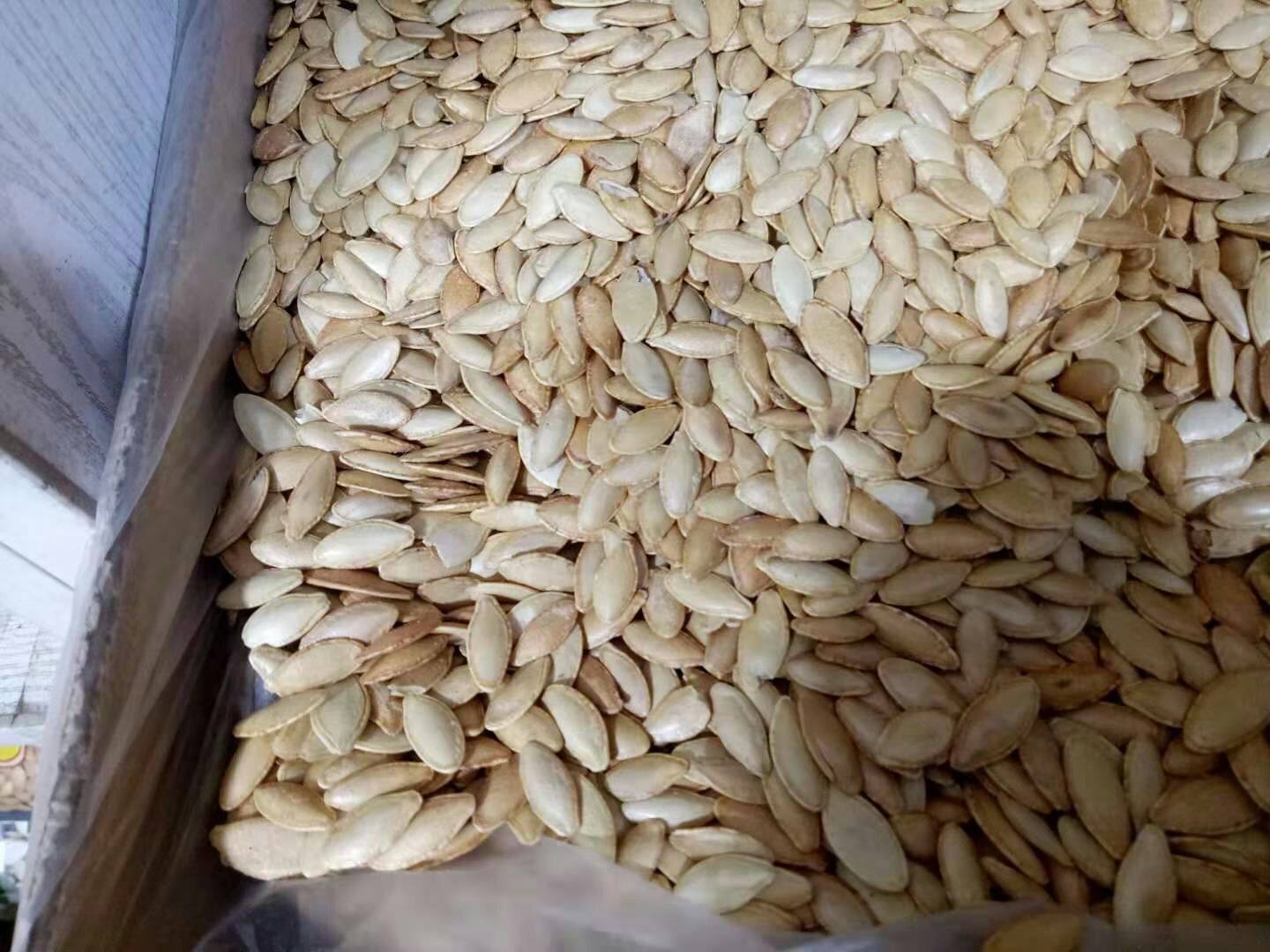一幅展示正规奶油南瓜种子包装的图片,包装上清晰标注品种名称、品种登记号、净含量、生产日期、生产商信息及二维码可追溯系统,背景为实验室检测人员使用显微镜检查种子纯度的场景 种子包装标识示例图