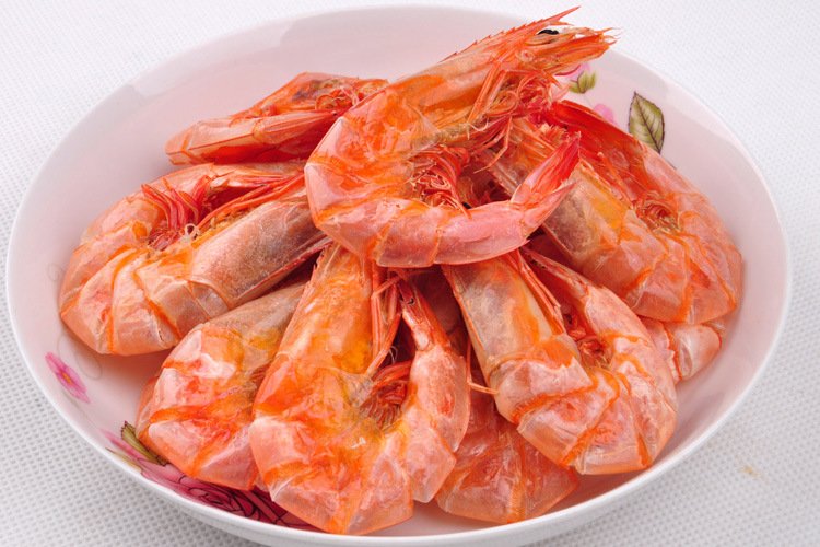 一盘煮熟的白对虾,呈现出典型的粉红色,虾壳略带透明,肉质紧实 煮熟的白对虾