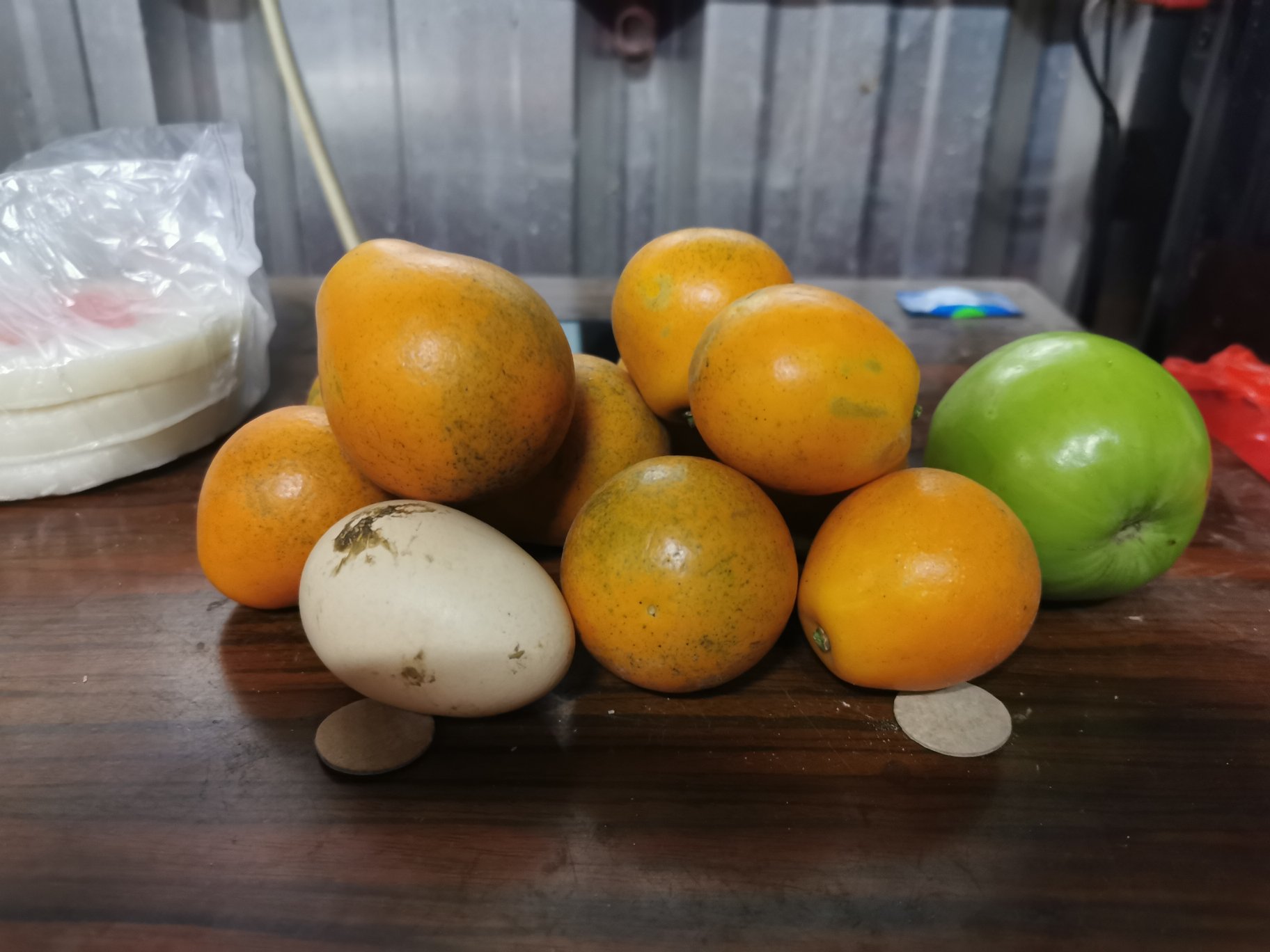 一位中年女性坐在餐桌前，面前摆放一小碟金桔（约3颗）、一杯温水和一份医疗记录本，神情专注地查看手中的化验单