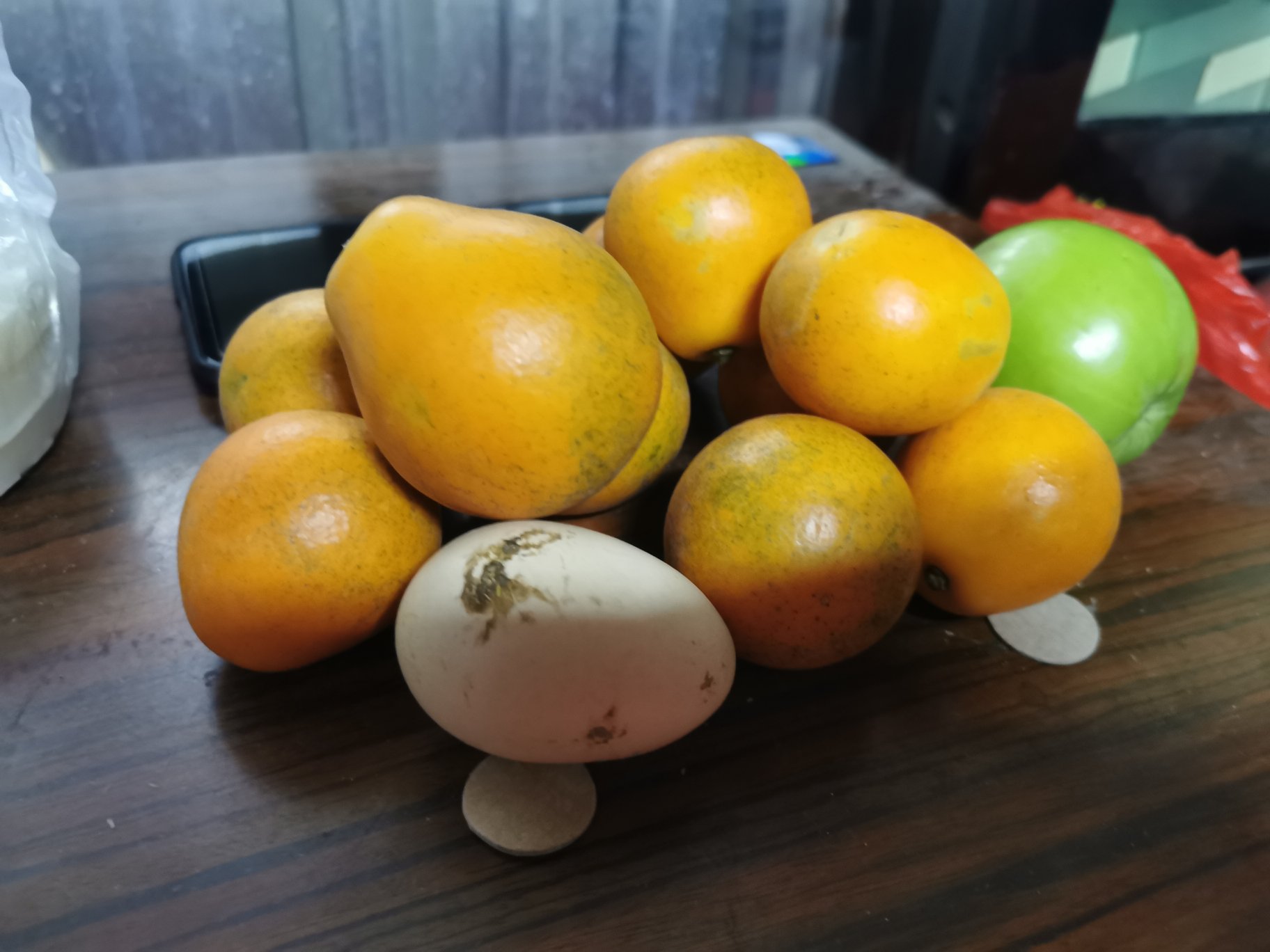 一组并列摆放的水果:左侧为金桔,个头小巧、色泽金黄;中间为普通橘子,较大、橙红色;右侧为柠檬,长椭圆形、亮黄色。背景为木质餐桌,上方标注‘金桔富含柠檬烯与类黄酮’字样,突出其营养特色 金桔与其他柑橘类水果对比图