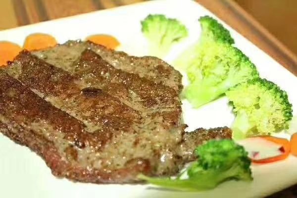 一份精致牛排套餐的俯拍图，主菜为五分熟西冷牛排，右侧搭配煎制西兰花、烤小土豆和番茄，整体色彩协调，摆盘美观