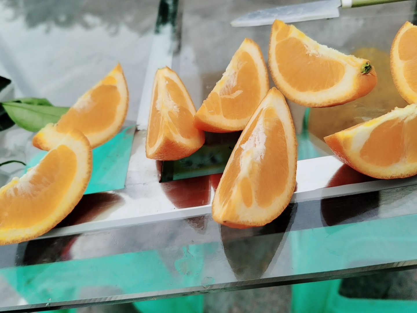 盐蒸香橙成品特写：一只剖开的盐蒸香橙横截面，外层橙皮呈透亮琥珀色且微卷，内侧白色海绵层饱满湿润，底部积聚浅金色澄澈汁液，旁置不锈钢小勺正刮取金皮层