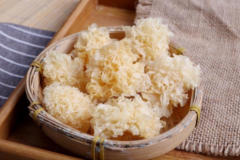 展示几朵完整、洁白的椴木银耳干品,摆放在竹篮中 挑选优质椴木银耳