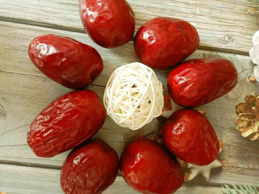 一盘新鲜的皮皮枣摆放在木质托盘上,枣子表面带有自然褶皱和光泽,部分已切开展示其厚实的果皮与饱满果肉,背景为浅色麻布纹理,突出天然健康主题 皮皮枣特写