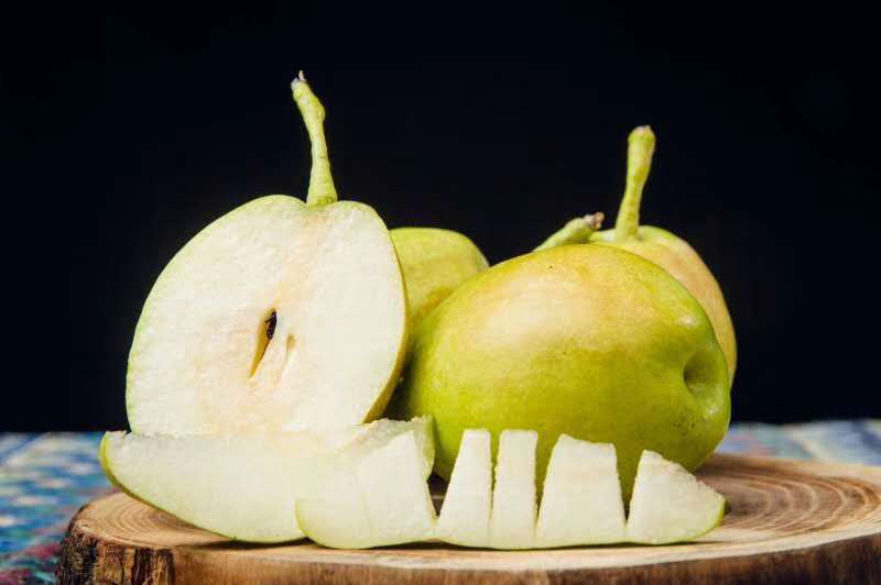 切开的香梨展示其洁白细腻的果肉,果汁丰富,背景为木质桌面 香梨切开展示果肉