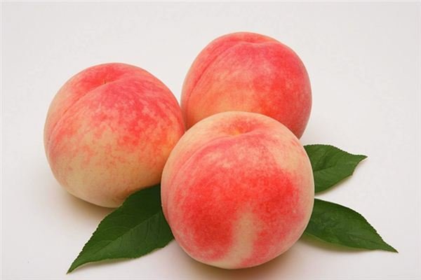 一颗被横向切开的中油18号油桃,露出金黄色的果肉,果核小且离核,果肉质地细腻无纤维感,果汁丰富,切面湿润有光泽,旁边摆放完整果实作为对比,背景为木质砧板,营造出自然健康的食品展示氛围 中油18号油桃切面展示