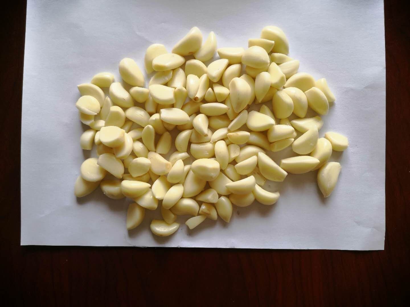 一位厨师正在厨房砧板上切碎白色蒜米,旁边配有橄榄油瓶、平底锅和新鲜蔬菜,展现蒜米在日常烹饪中的应用,强调其作为健康调味食材的角色 家庭厨房中的蒜米使用场景