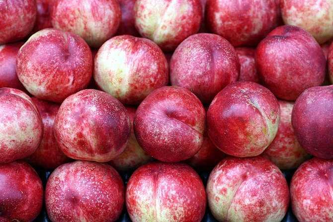 剖面特写:清晰呈现518油桃‘核小肉厚、汁多色正、离核易食’三大新鲜品质特征,强化视觉信任感与食用场景联想 518油桃切开展示:横切一刀露出金黄透亮的果肉,纹理细腻均匀,核小离肉明显,汁液微微渗出边缘;旁边摆放完整油桃、绿叶与玻璃水杯(盛有淡粉色桃汁),构图清新富有食欲感