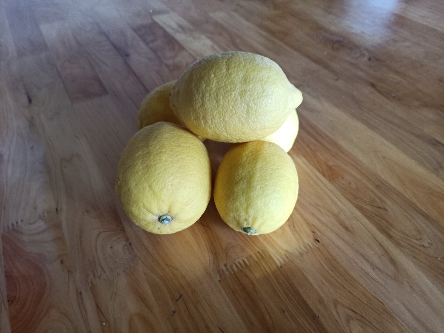 一颗金黄色的安岳柠檬放置在木质砧板上,表面光滑有光泽,旁边有一把不锈钢水果刀和一片切开的柠檬,展示其饱满多汁的果肉结构 安岳柠檬特写