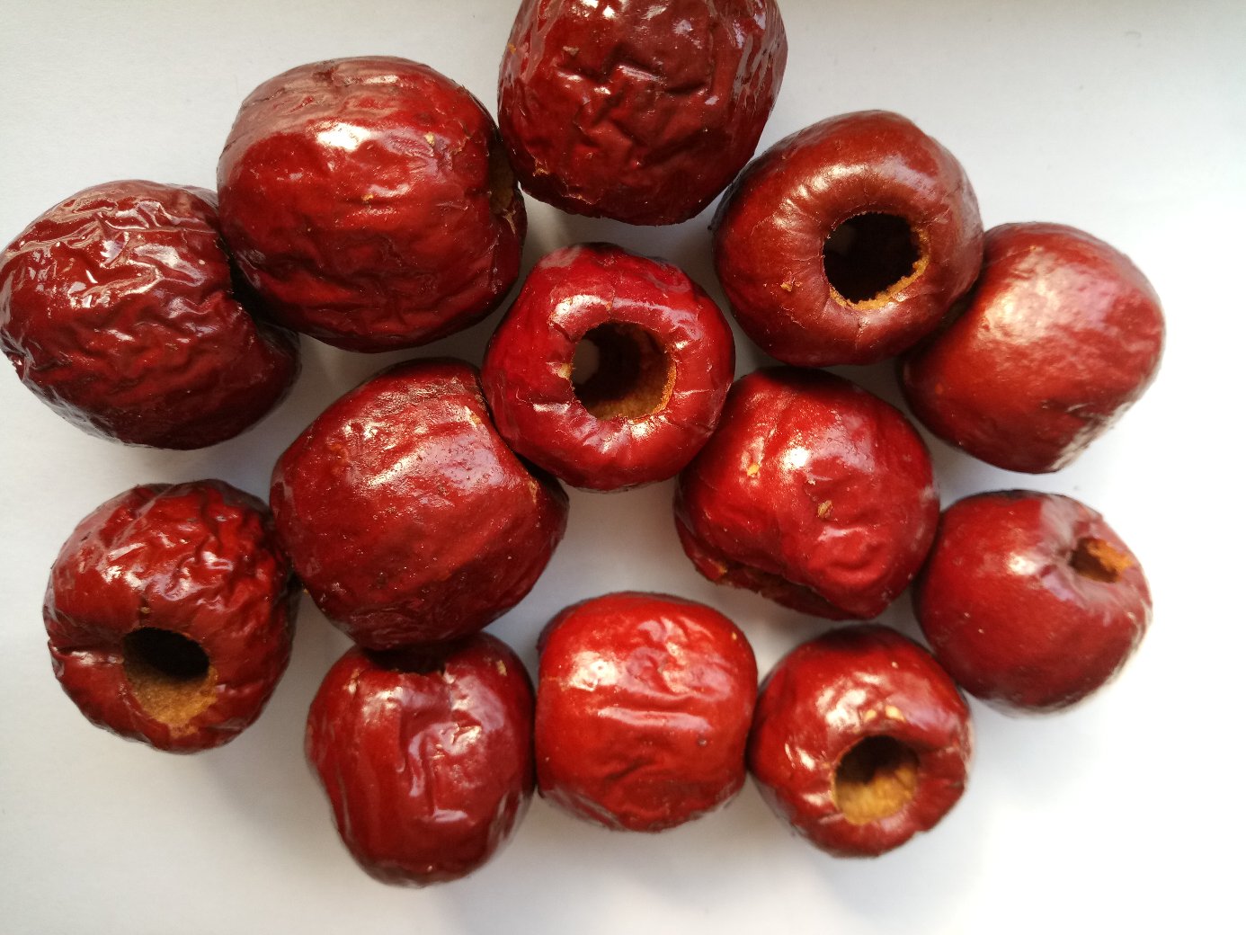 消费者选购场景还原,展示‘鲜枣红’鲜枣的新鲜状态与典型外观,强调带柄、无损、色泽均匀 一位女性手持新鲜采摘的鲜枣,背景为清晨果园,露珠尚存,手中鲜枣呈现出典型的‘鲜枣红’色泽,部分果实仍带果柄