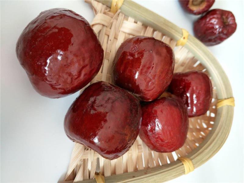 成熟冬枣在果园中刚被采摘,成堆放置于竹编筐内,光线明亮,展现果实饱满、色泽红润的特写画面 新鲜采摘的冬枣堆放在竹筐中,阳光照射下果皮泛着光泽,背景为果园树木