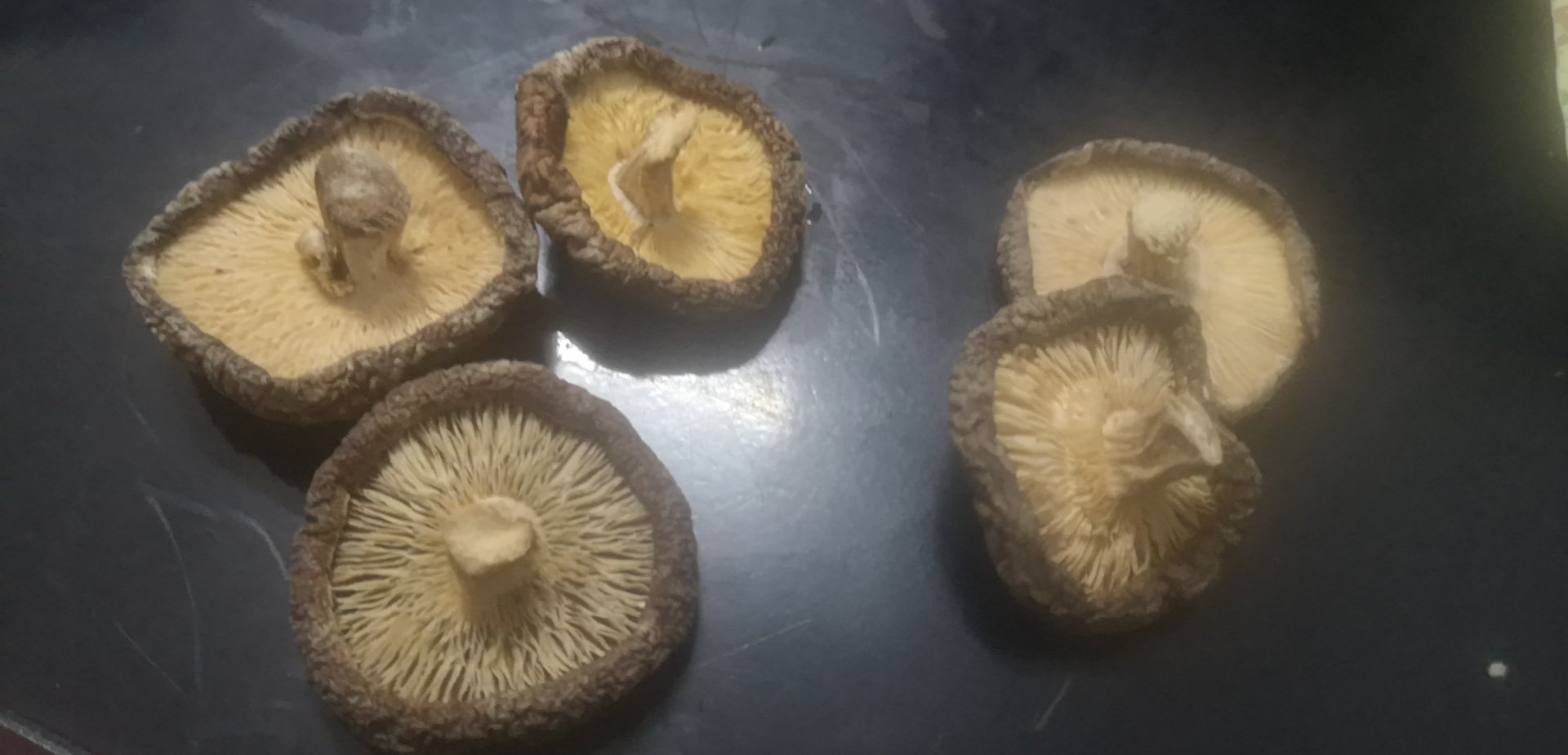 展示几朵完整的干香菇,表面带有自然裂纹,背景为木质桌面 干香菇实物图