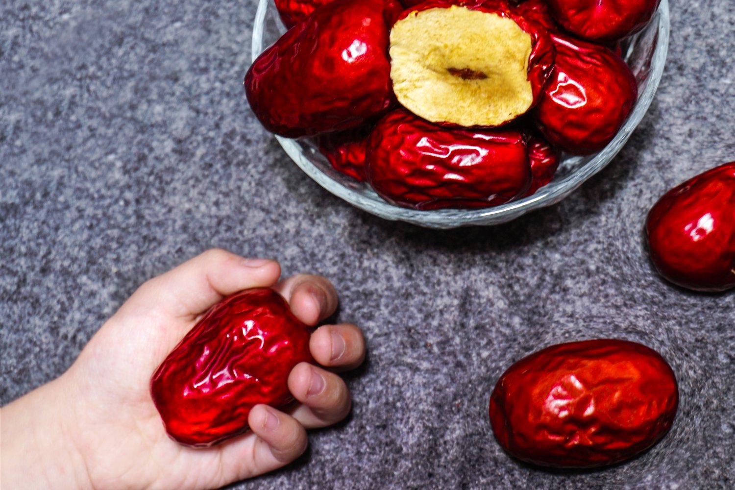 一碗正在熬制的红枣小米粥,锅中漂浮着数颗裂口的骏枣,旁边摆放着整颗骏枣和去核骏枣,展示其在日常饮食中的多种用途 骏枣烹饪应用