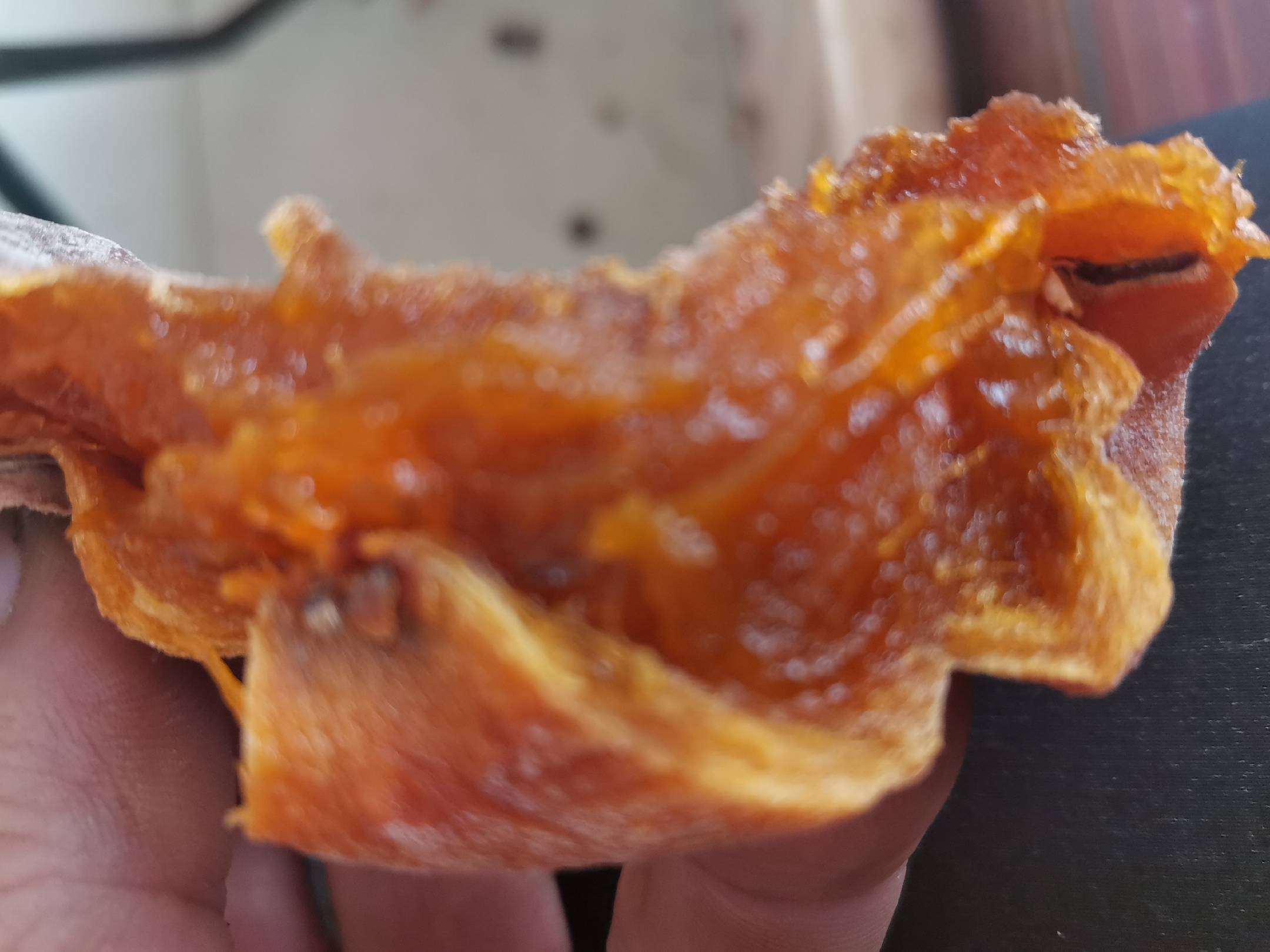 一张切开的磨盘柿照片,展示其橙红色果肉与内部结构,背景为木质桌面 磨盘柿切开图