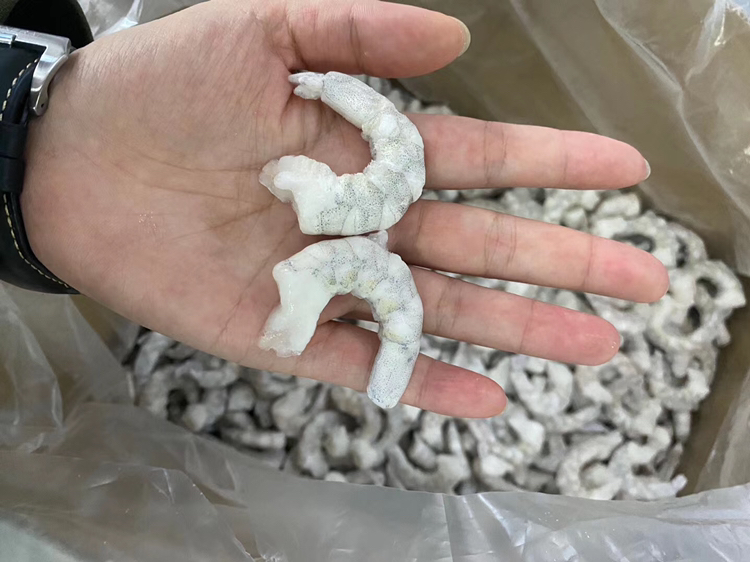 锅中热水正在焯烫虾仁,旁边放有姜片和料酒瓶 焯水虾仁过程图