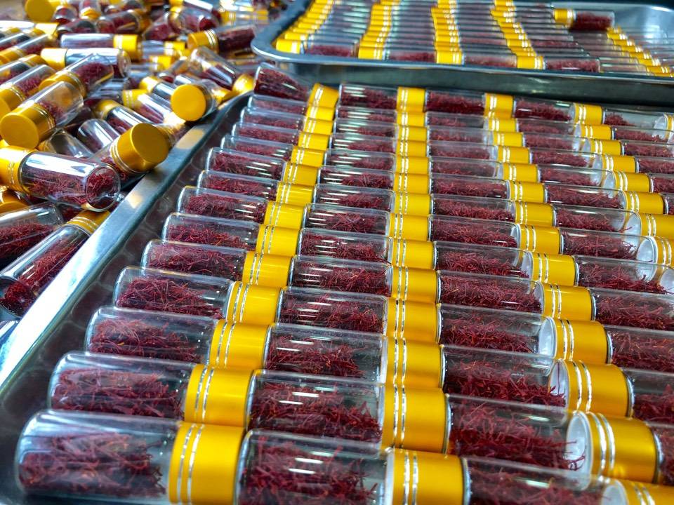 两张并列照片展示高品质农产品包装:左图为密封罐装野生野菊花,标签注明产地河南、采收日期、SC编号;右图为小玻璃瓶装伊朗进口藏红花,配有防伪码和成分检测卡,背景为浅灰色布纹,突出产品的专业性和可信度 优质野菊花与藏红花成品包装展示图