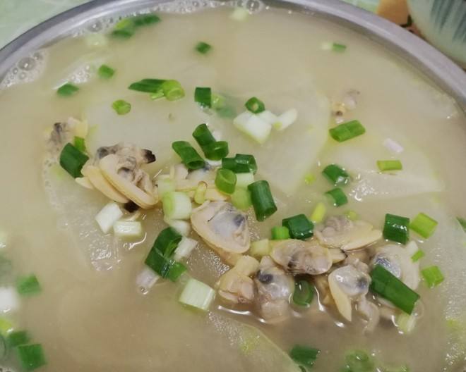 特写镜头:青白相间的冬瓜片悬浮于清澈汤中,嫩豆腐块完整柔润,花蛤微微张口露出金黄蛤肉,汤面浮着细小葱花与三滴香油光泽,整体呈现清透温润的夏日养生汤质感 冬瓜花蛤豆腐汤成品特写