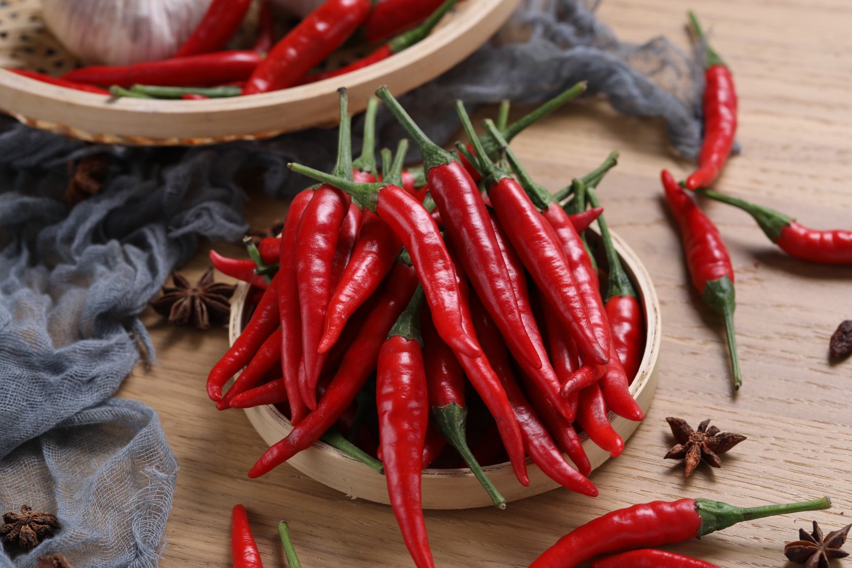 特写镜头展示一堆完全干燥的红色干辣椒,表面褶皱清晰,颜色深红带棕,部分已被剪成小段,旁边放置一个陶瓷碗,内有红色辣椒碎末,整体呈现温暖质朴的乡土风格 干辣椒特写展示