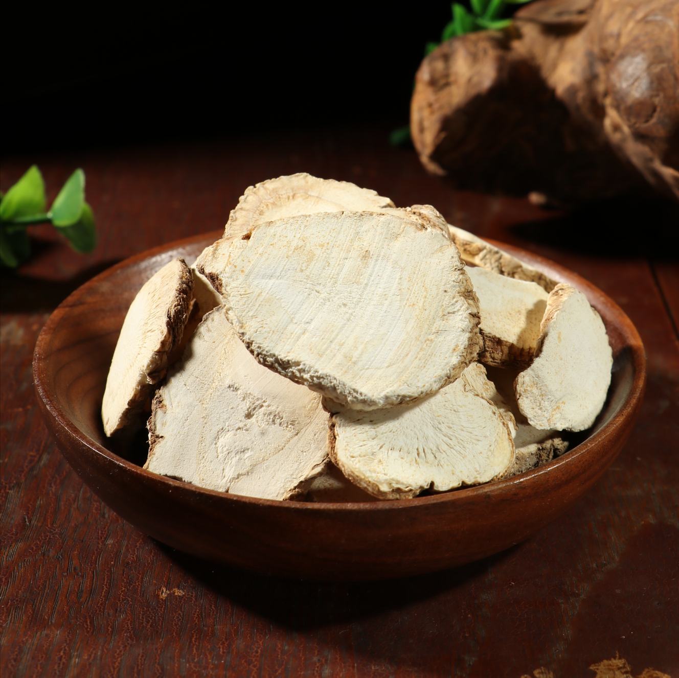 中式厨房操作台上放置一碗切片的干燥白芷,旁边配有八角、桂皮、草果等香料;锅中正在炖煮牛肉,汤面上漂浮着香料,热气腾腾,体现白芷作为调味料的实际应用场景 白芷在厨房中的应用场景