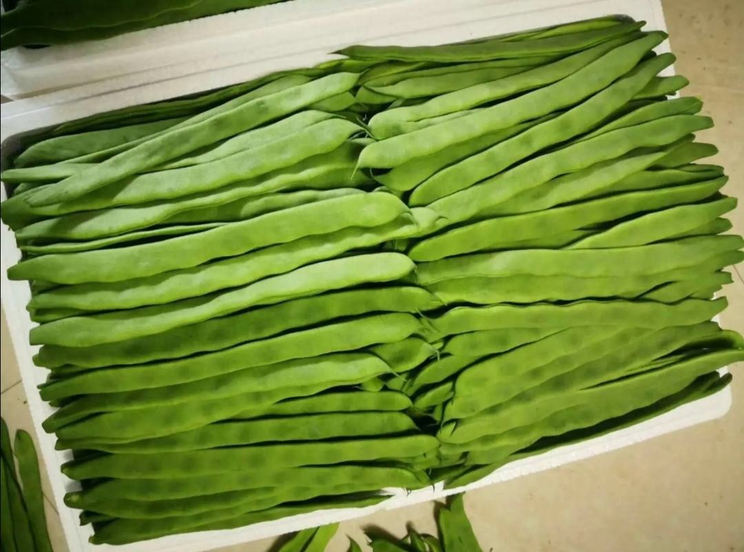 新鲜扁豆与山药摆放在木质砧板上，旁边有大蒜、生姜、红椒等辅料整齐排列，背景为厨房操作台