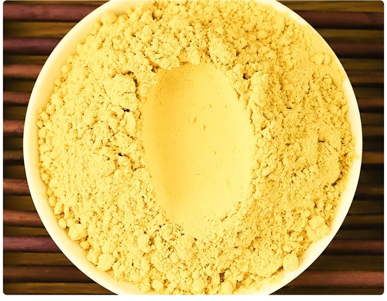 厨师正在白色案板上揉制掺入浅黄色老姜研粉的面团,面团已呈现微黄色泽,旁边放置小碗盛有姜粉,背景可见蒸笼和厨房工具 老姜研粉加入面团揉制过程