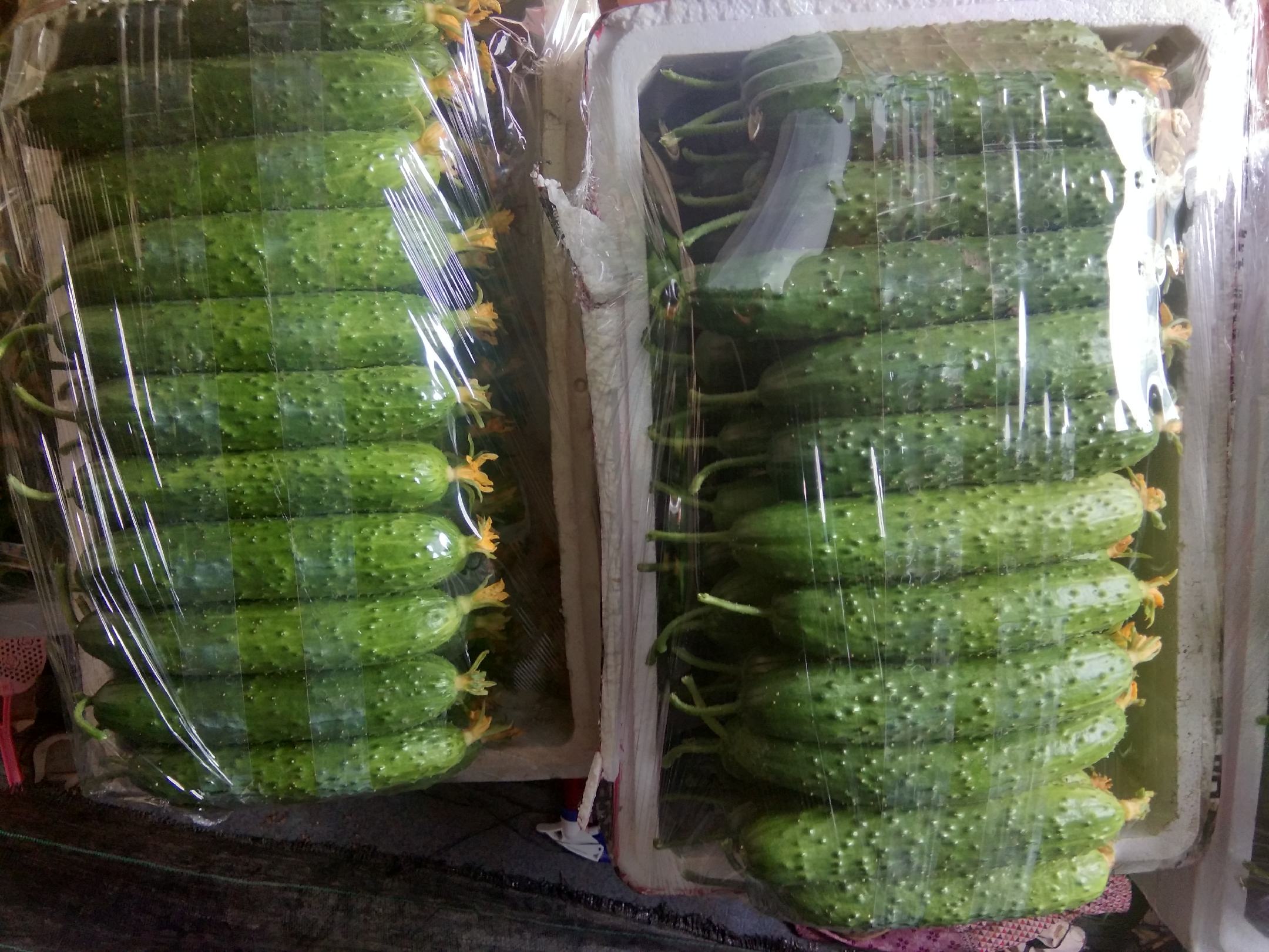 清洗后的小黄瓜整齐摆放在案板上，表面带有细小绒刺，色泽鲜绿，背景为木质厨房台面