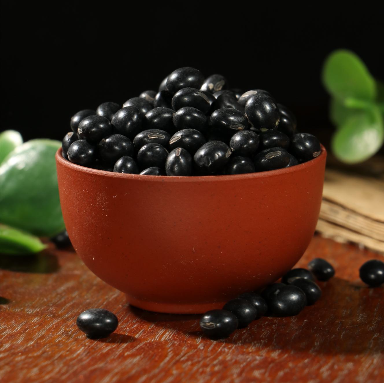 一盘新鲜煮熟的黑豆,颗粒饱满,色泽乌黑发亮,表面带有自然光泽,背景为木质餐桌,旁边放置一个小勺,突出其作为健康食材的真实质感 黑豆特写镜头