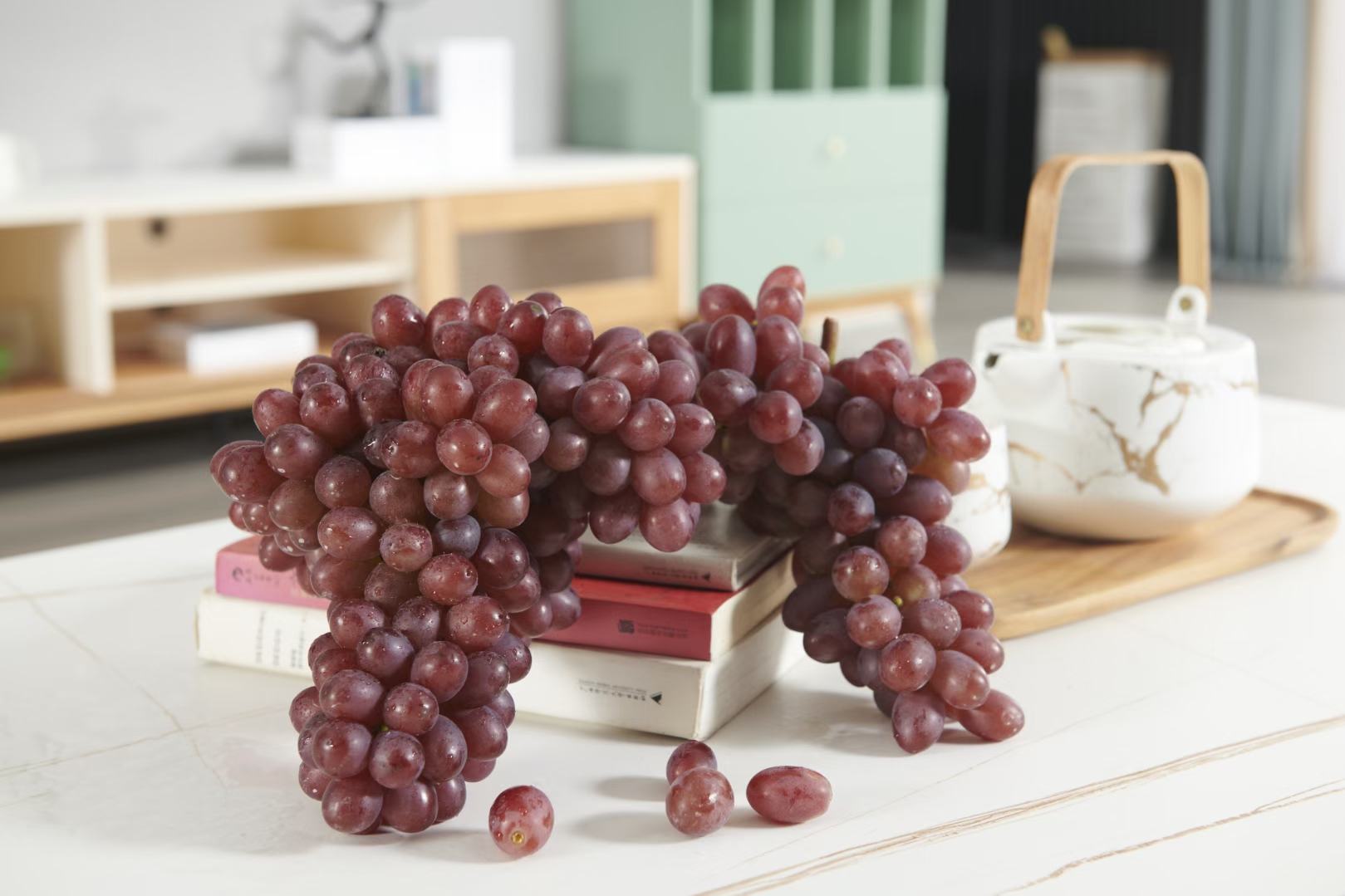 一张白色大理石餐桌上,摆放着一份精致的冷餐拼盘:左侧是一串完整的克伦生葡萄,右侧是切块的奶油奶酪、坚果仁和无花果,中间点缀薄荷叶,整体色彩对比鲜明,突出克伦生葡萄作为健康食材的高级感与百搭特性 克伦生葡萄美食创意摆盘