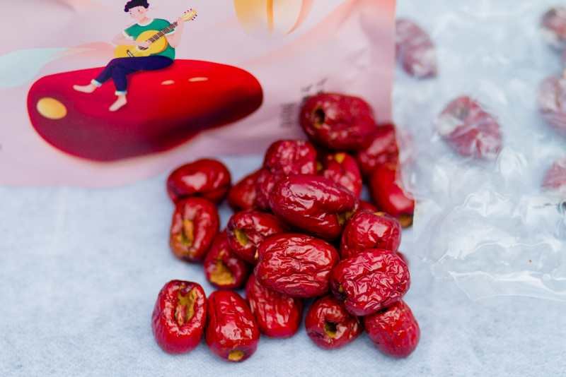 信息可视化插画风格工艺流程图,突出冰糖脆枣‘三步核心工艺’,画面干净专业,色调以暖金、象牙白与浅木棕为主,体现食品级洁净生产环境与现代化加工水准 冰糖脆枣制作工艺示意图:左侧为新鲜青红相间的大枣原料,中部为不锈钢糖渍缸中浸泡于澄澈冰糖液的半成品枣,右侧为自动化脆化设备出口处喷出的金黄色脆枣颗粒,三阶段并列呈现,辅以简洁图标标注“选枣→冰糖浸渍→真空脆化”