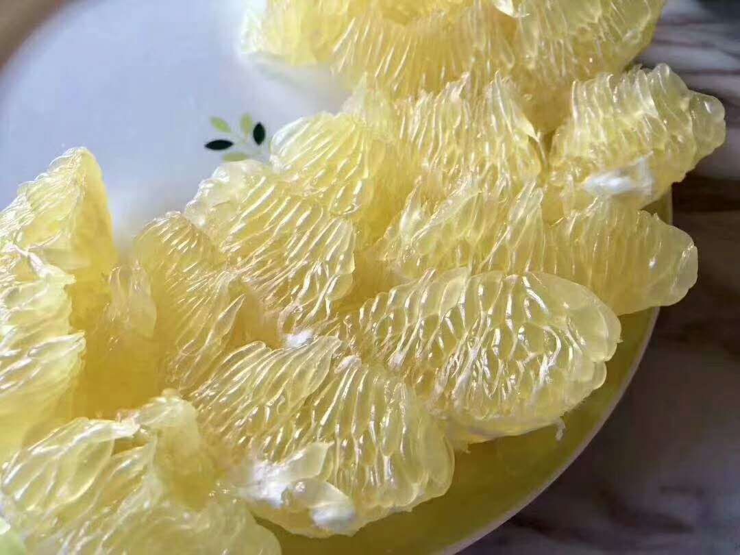 展示一杯装在透明玻璃杯中的蜜柚果汁饮料,颜色淡黄,有果肉悬浮,杯口有柠檬片装饰 蜜柚果汁成品展示