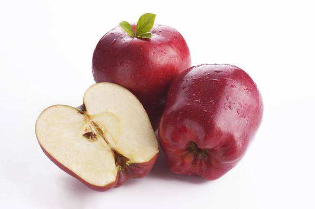 一个新鲜采摘的花牛苹果被横向切开,展示其乳白色果肉与明显较厚的红色果皮结构,果皮厚度约占整个果壁的1/6,表面带有天然果粉 花牛苹果横切面特写