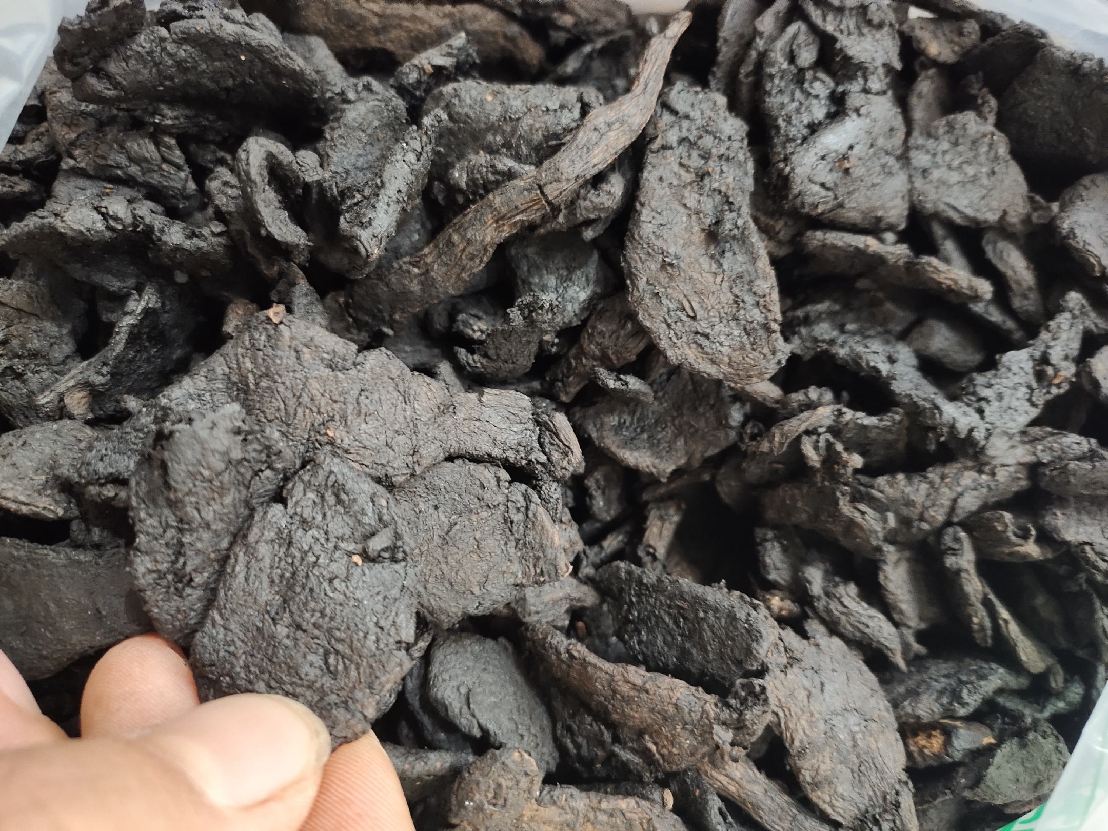 高清实物图展示:左侧为淡黄色纺锤形麦冬块根,表面有细纵纹,质地柔韧;右侧为乌黑色熟地黄切片,油润光泽,呈团块状或不规则厚片,断面黏稠。背景为传统中药柜与研钵,体现中医药文化氛围 麦冬与熟地黄药材对比图