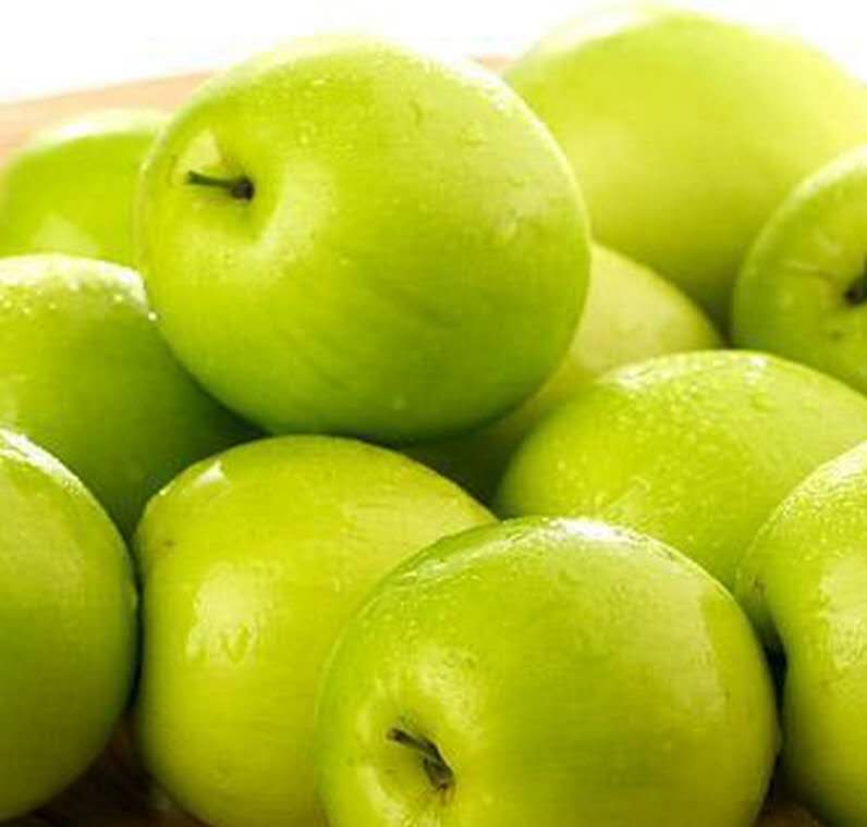 一颗新鲜青枣的特写镜头,果皮呈翠绿色略带微黄,表面光滑无划痕,果形饱满圆润,顶部果萼清晰可见,背景为自然光线下的竹编果篮 青枣果实特写