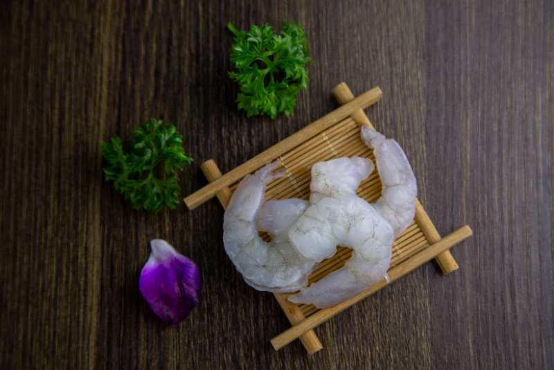 新鲜螺丝椒与去壳虾仁整齐摆放在案板上,背景为厨房环境 螺丝椒与虾仁原材料展示